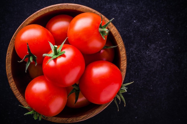 Świeże organiczne pomidorki koktajlowe w misce zbliżenie na ciemnym tle
