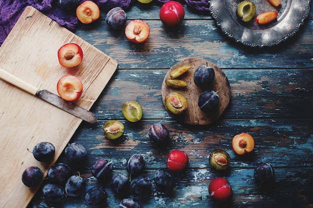 Świeże organiczne śliwki i plastry śliwki na drewnianej desce i rustykalnym drewnianym stole jesienne zbiory owoce sezonowe zdrowy styl życia widok z góry selektywne skupienie