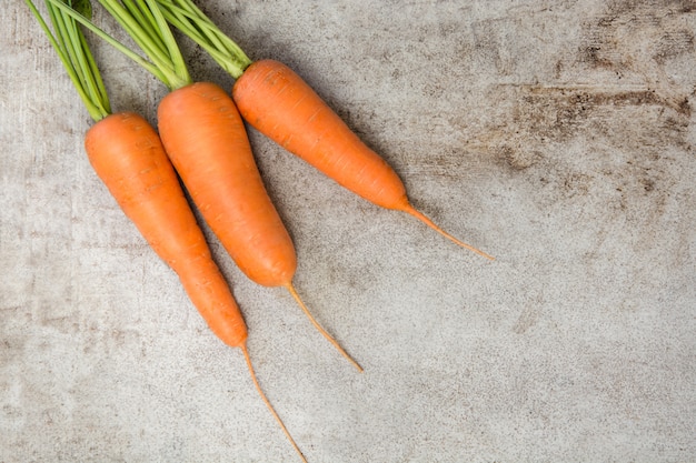 Świeże organicznie marchewki z zielonymi wierzchołkami na wieśniaka stole. Skopiuj miejsce. Widok z góry.