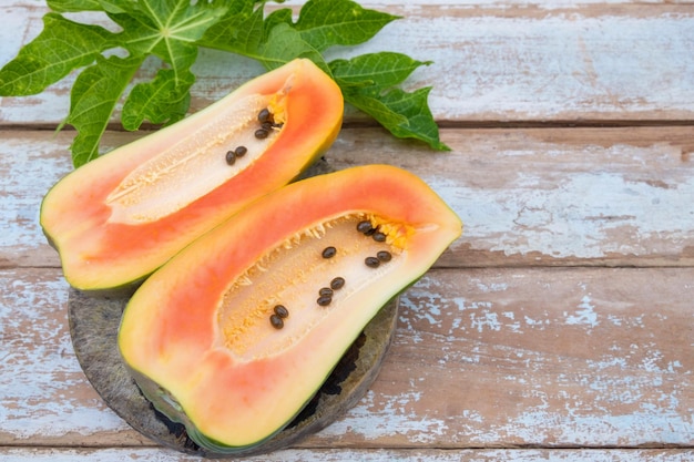 Świeże owoce papai pokrojone na pół na drewnianym tle