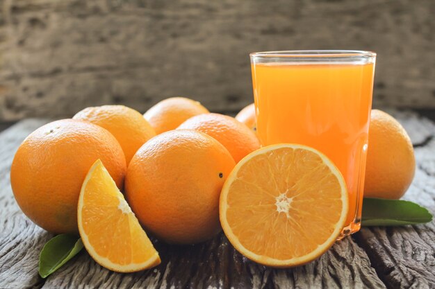 Świeże owoce pomarańczy z liśćmi na drewnianym stole Szkło świeżego soku pomarańczowego