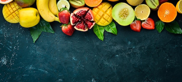Świeże owoce tropikalne na czarnym tle Melon cytrusowy Granat Truskawka Banan Widok z góry Wolne miejsce na tekst