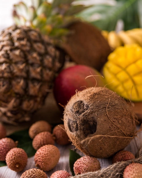 Świeże owoce tropikalne na widok z góry drewna. banany, ananas, kokos, mango, liczi, kasztany. Stonowany.