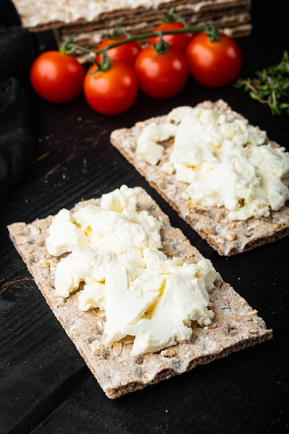 Świeże pieczywo chrupkie żytnie z innym zestawem dodatków, na czarnym drewnianym stole w tle