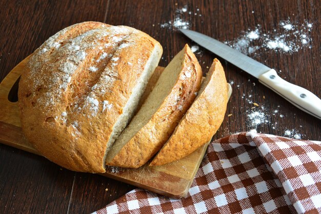 świeże pieczywo z kromkami chleba na desce do krojenia z nożem