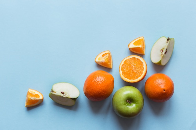 Świeże pomarańcze i zielone jabłka na niebieskiej powierzchni