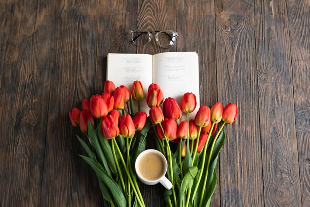 Zdjęcie Świeże pomarańczowe tulipany z otwartą książką lub pamiętnikiem na drewnianym tle