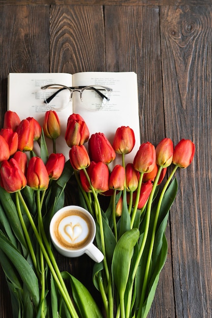 Zdjęcie Świeże pomarańczowe tulipany z otwartą książką lub pamiętnikiem na drewnianym tle