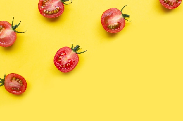 Świeże pomidory całe i pół pocięte na białym tle na żółtym tle