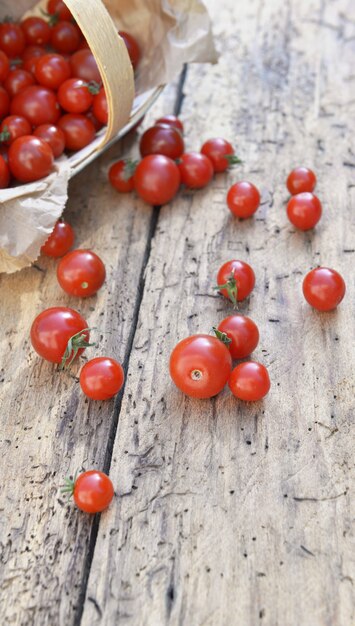 Świeże pomidory czereśniowe rozlane na rustykalnej desce