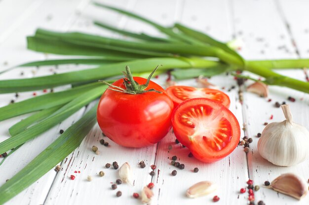 Świeże pomidory z przyprawami. Ekologiczna zdrowa żywność na drewnianym Zielonym czosnku. Warzywa letnie i jesienne.