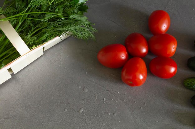 Świeże pomidory, zielone ogórki i pachnąca sałatka z zielonych warzyw w bambusowym koszu ułożonym dokładnie w rzędzie na kuchennym stole