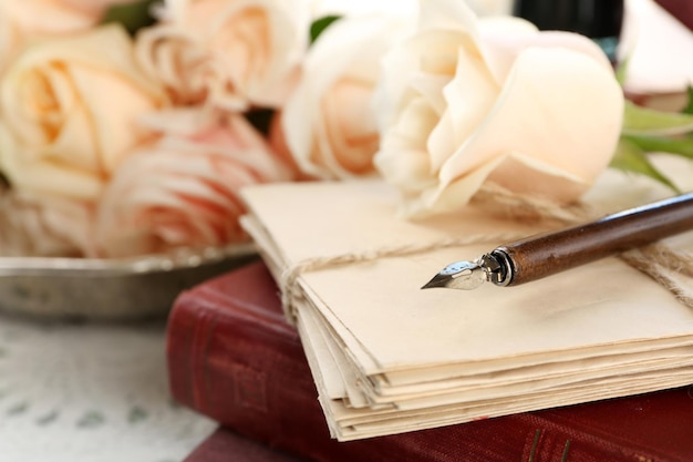 Zdjęcie Świeże róże ze starej książki i litery na drewnianym stole kolor tła. koncepcja vintage