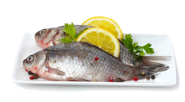 Świeże ryby z cytryną i pietruszką na talerzu na białym tle