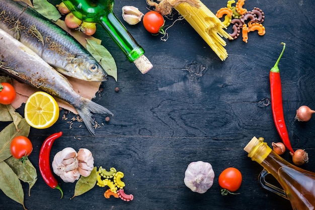 Świeże ryby z warzywami, przyprawami i olejem Na czarnym drewnianym tle Wolne miejsce na tekst Widok z góry