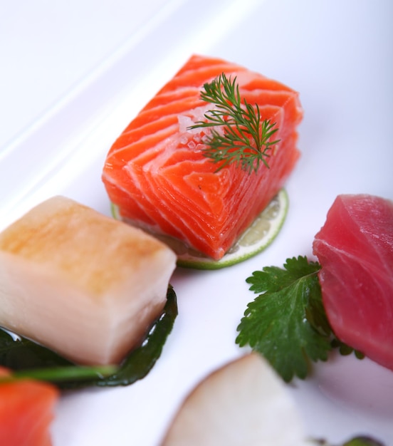 Świeże sashimi ozdobione zielenią i limonką. Zbliżenie