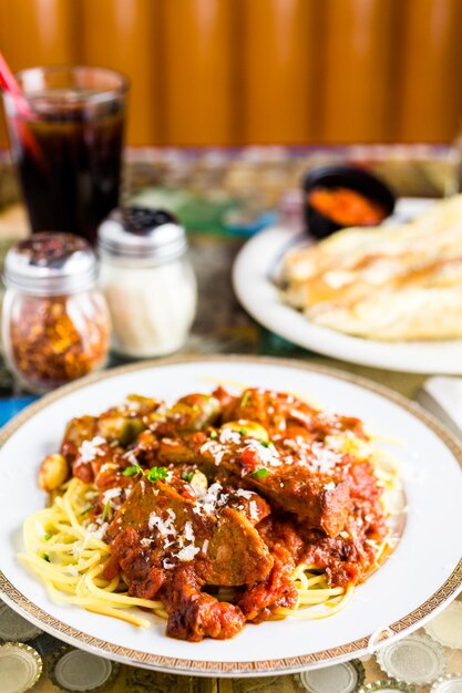 Świeże spaghetti z kiełbasą, papryką i cebulą we włoskiej restauracji.