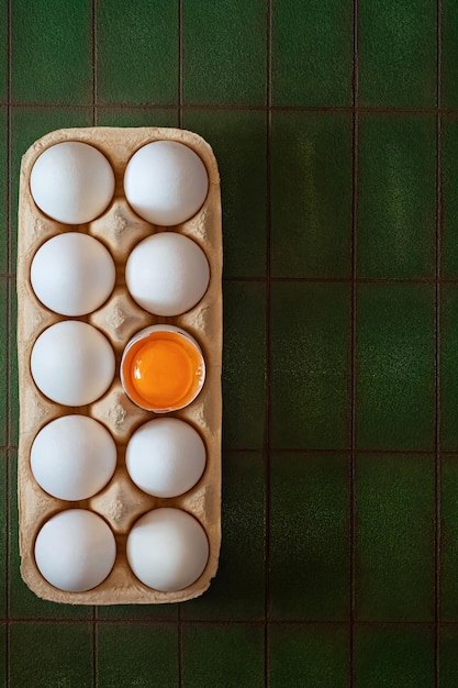Zdjęcie Świeże surowe jaja w kartonowej tacy na zielonym tle