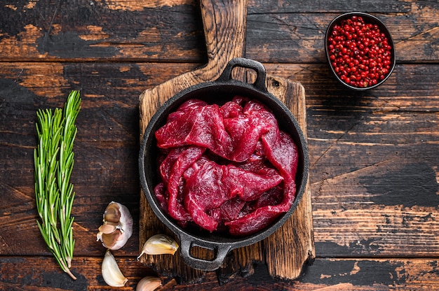 Świeże surowe plastry mięsa z czerwonej wołowiny w kostkę na żeliwnej patelni