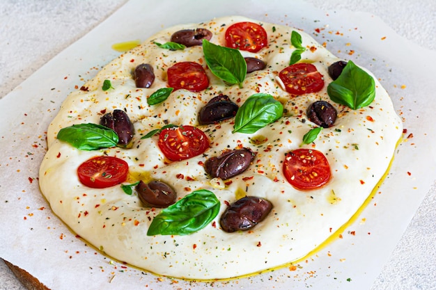 Świeże włoskie płaskie pieczywo (surowe) Focaccia z pomidorami, oliwkami, czosnkiem i ziołami