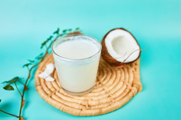 Świeże, zdrowe mleko kokosowe w szklance na niebieskiej powierzchni