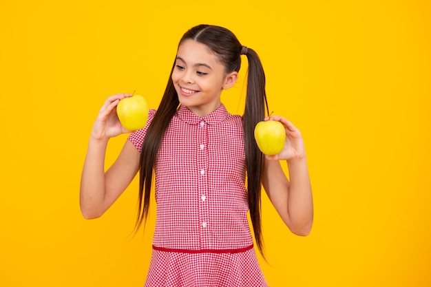 Świeże zielone jabłko Nastolatek dziewczyna trzyma jabłka na żółtym tle studyjnym na białym tle Żywienie dzieci Szczęśliwa dziewczyna twarz pozytywne i uśmiechnięte emocje Szczęśliwa nastolatka pozytywna i uśmiechnięta