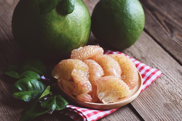 Świeże zielone pomelo obrane i liść z drzewa pomelo grejpfrut pummelo latem owoce tropikalne w tajlandii owoce pomelo na tle drewnianej płyty