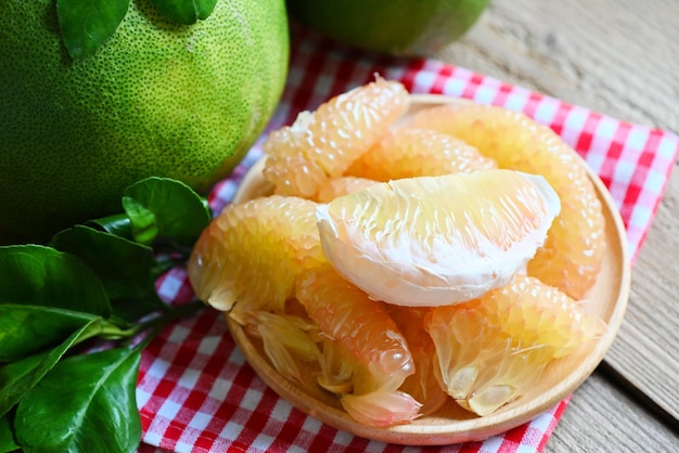 Zdjęcie Świeże zielone pomelo obrane i liść z drzewa pomelo grejpfrut pummelo latem owoce tropikalne w tajlandii owoce pomelo na tle drewnianej płyty