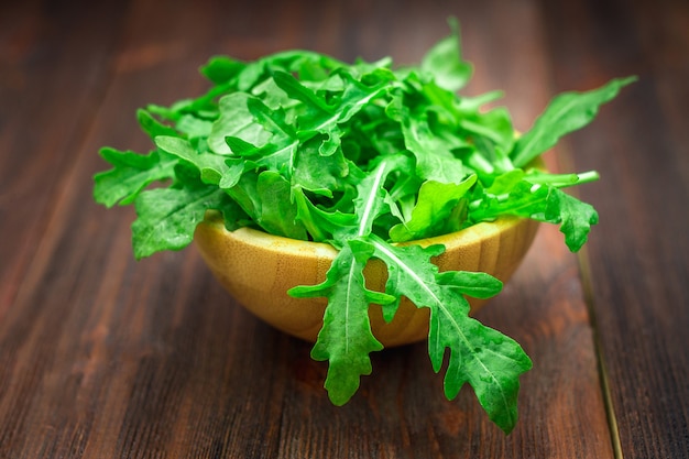 Świezi soczyści liście arugula na brown drewnianym stole.