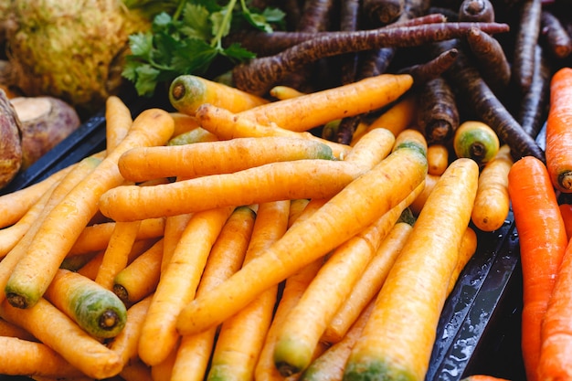 Świezi surowi organicznie niegotowani marchwiani warzywa dla sprzedaży przy rolnikami wprowadzać na rynek. Wegańskie jedzenie i zdrowe odżywianie.