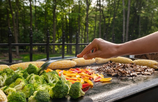 Zdjęcie Świeżo grillowane pieczarki kukurydziane z grilla papier i brokuły osoba grillująca zdrowe warzywa