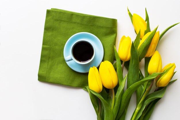 Świeżo parzona kawa na zielonej serwetce z żółtymi tulipanami