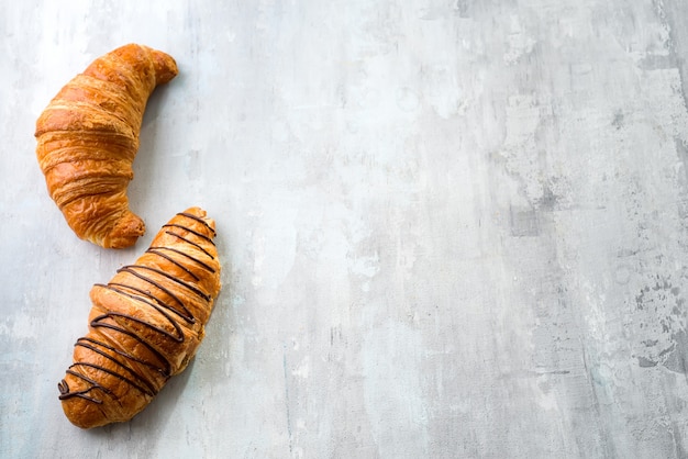 Świeżo piec croissant dekorował z czekoladowym kumberlandem odizolowywającym na szarym łupkowym tle