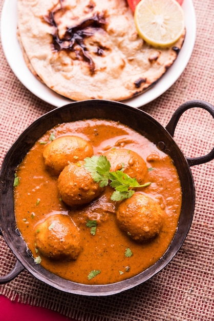 Świeżo ugotowane pikantne curry ziemniaczane na patelni lub Gorące i pikantne Dum aloo podawane z tandoori roti lub naan lub indyjskim chlebem lub chapati i zieloną sałatą, selektywne skupienie