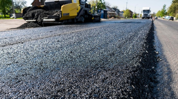 Świeżo ułożony czarny asfalt bitumiczny z wysoką krawędzią do żwiru ukazującą strukturę