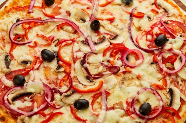 Świeżo upieczona pizza wegetariańska z pomidorami, pieczarkami, czerwoną papryką, oliwkami, cebulą i mozzarellą podawana na drewnianym tle z sosami i ziołami Koncepcja dostawy żywności Menu restauracji