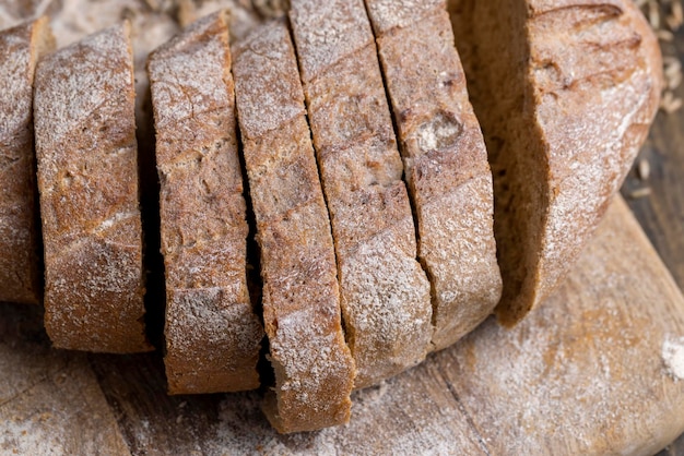 Zdjęcie Świeżo upieczony bochenek ciemnego chleba pokroić na kawałki bochenek miękkiego świeżego chleba żytniego z drożdżami