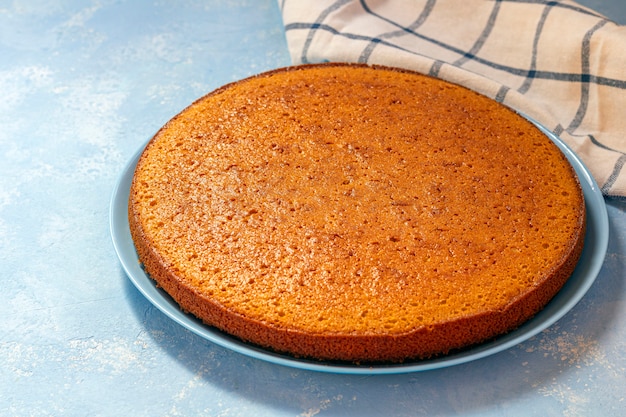 Świeżo upieczony nieobrobiony placek marchewkowy, tarta cytrynowa lub ciasto z kaszy manny na niebieskim talerzu.