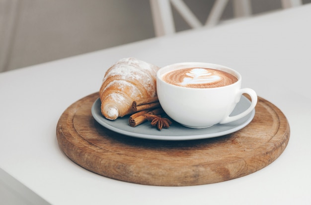 Świeżo upieczony rogalik z filiżanką kawy i latte art