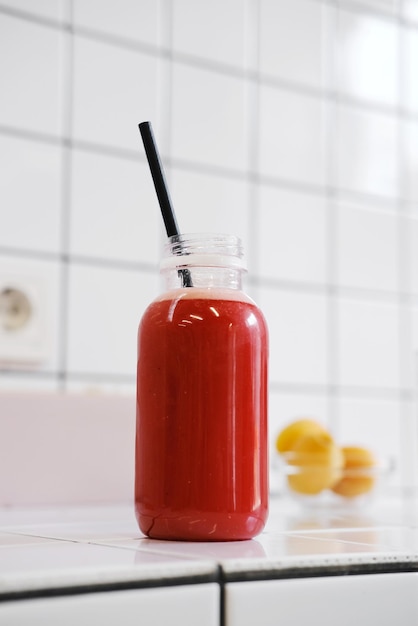 Świeżo wyciśnięty sok z arbuza w plastikowej butelce ze słomkami na tle białych płytek ceramicznych