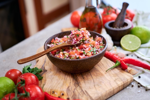 Świeżo zrobiony sos salsa z posiekanymi pomidorami czosnkowymi i cebulą w drewnianej misce