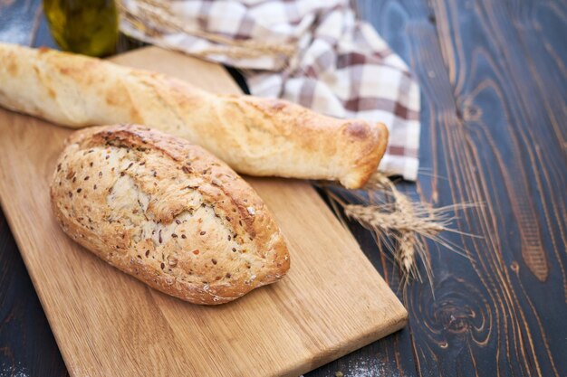 Świeży bochenek chleba i bagietka na drewnianej desce do krojenia przy stole kuchennym