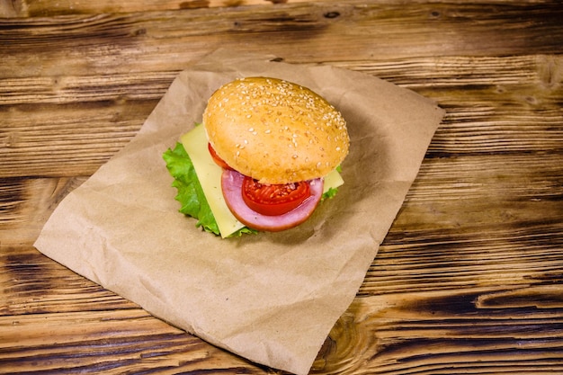 Świeży hamburger na brązowym papierze na drewnianym stole