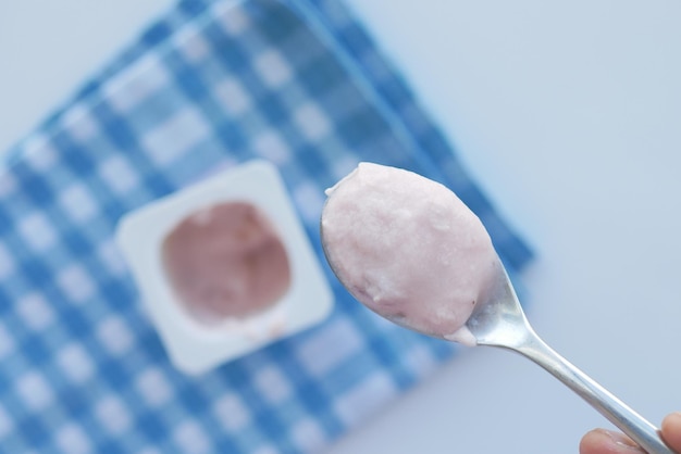 Świeży jogurt w plastikowym pojemniku i łyżka na stole