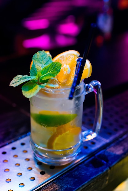 Świeży koktajl mojito z miętą limonkowo-rozmarynową i lodem w szklanej szklance na czarnym tle