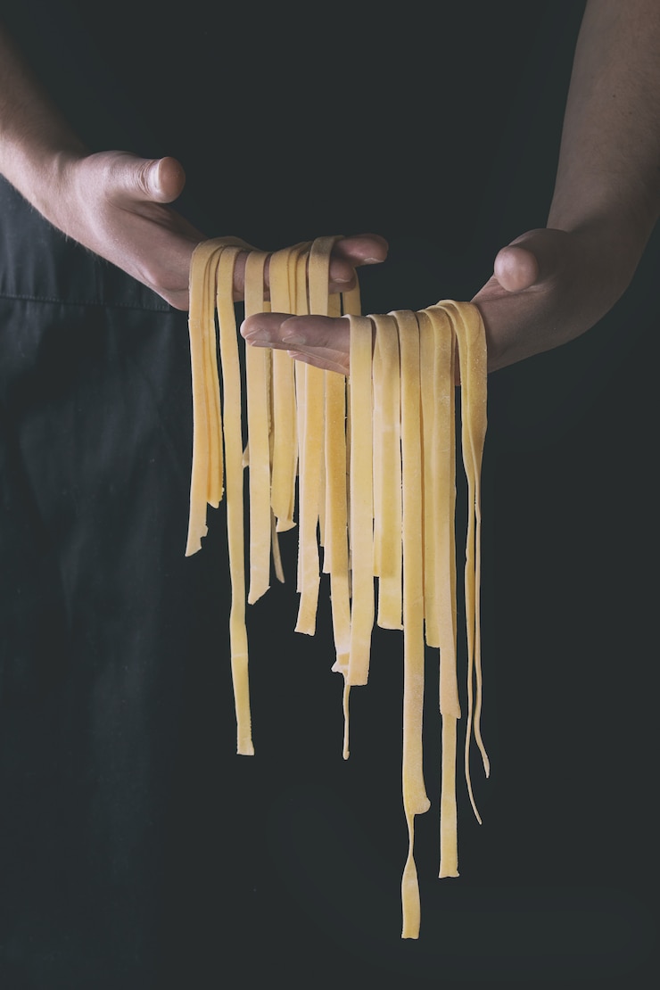 Zdjęcie świeży makaron tagliatelle w ręce mężczyzny