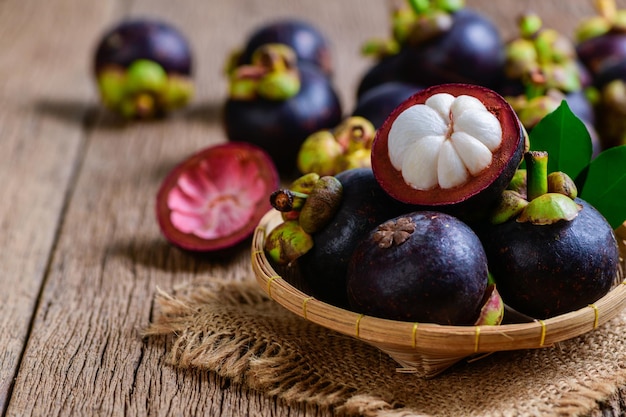 Świeży mangostan w bambusowym koszu i na starym drewnianym tle