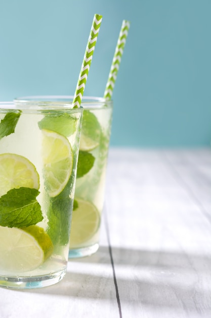 Świeży mojito w szkle z wapnem i mennicą na białym drewnianym stole i błękicie