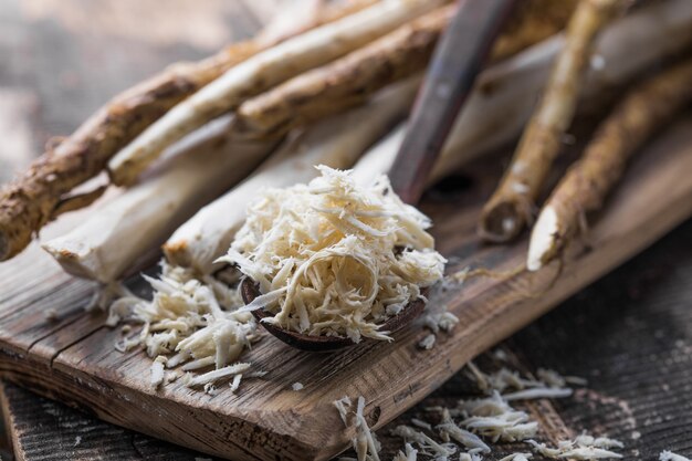 Świeży organiczny chrzan lub korzeń chrzanu na drewnianej desce do krojenia.