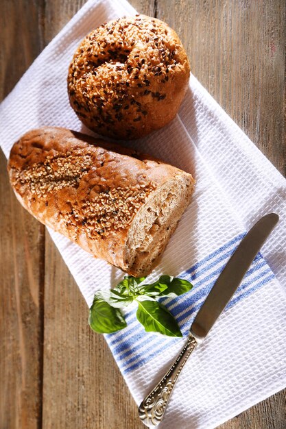 Zdjęcie Świeży pieczony chleb i świeża bazylia na ręczniku kuchennym na drewnianym tle